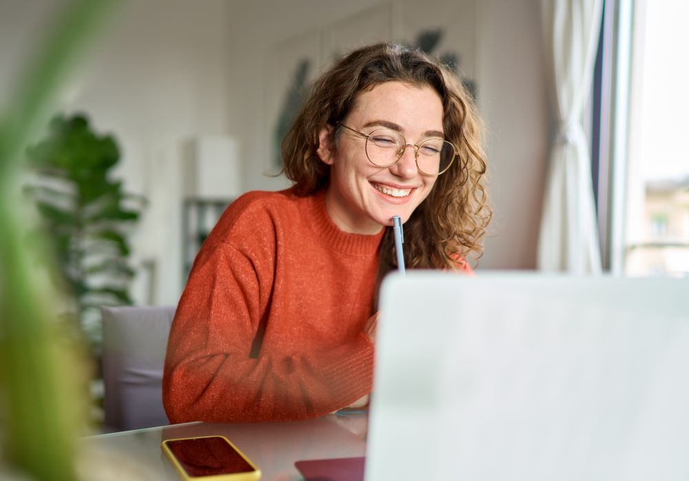 Young woman smiling while looking at the laptop