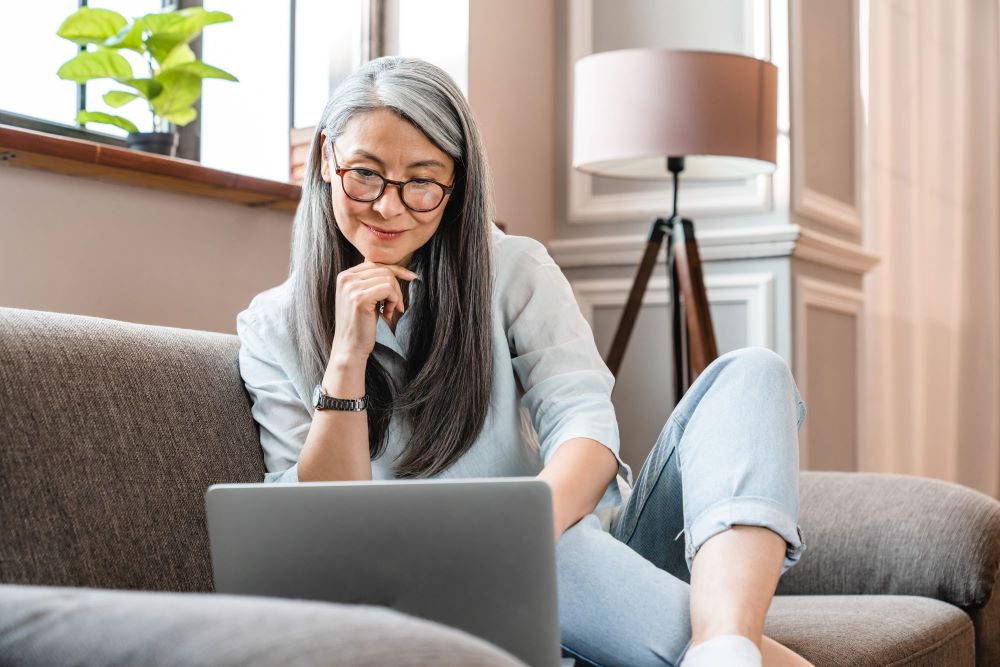Woman looking at the laptop sitting on a couch 